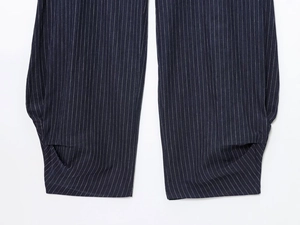 Detailed close-up of vertical pinstripe navy trousers featuring unique folded hem design