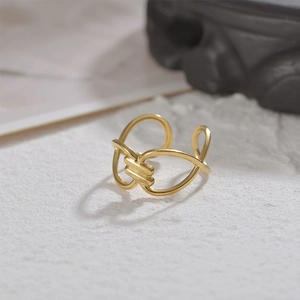Detailed macro view of an elegant 14K gold minimalist intertwined knot ring on white stone