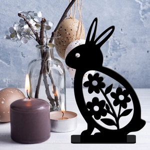 Detail of black hollow Easter bunny acrylic ornament with flower patterns on white wood table