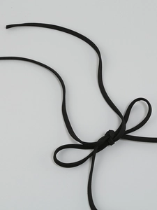 Macro detail of sexy backless dress featuring thin black elastic ties in a bow tie knot