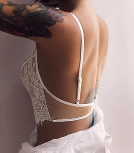 Detail of white eyelash lace bra featuring a backless design with thin spaghetti straps