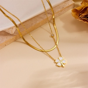 Detail of gold double-layer necklace featuring clover pendant with white shell inlay