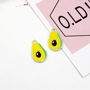 Close-up of enamel avocado charms with golden edges and vibrant green and yellow colors