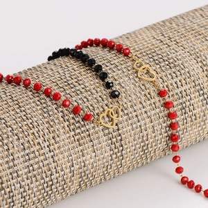 Minimalist red and black faceted bead bracelets with gold heart charms on a display stand
