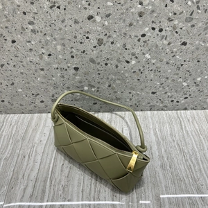 Detailed close-up of a green woven leather hobo bag with gold hardware on marble surface