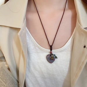 Detail of heart-shaped natural purple stone pendant on a woven cord necklace