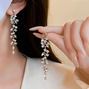 Detail of silver long tassel leaf earrings with sparkling cubic zirconia on a model