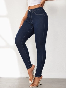 Detail of high waisted skinny denim jeans featuring white contrast stitching and dark blue wash