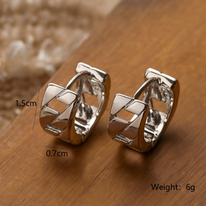 Detail view of silver heart earrings with woven texture showing 1.5cm height and weight
