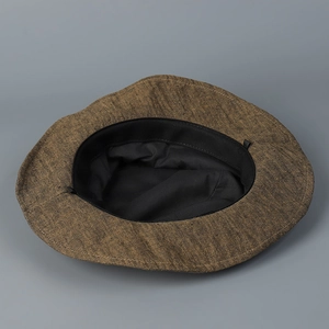 Interior detail view of a distressed linen bucket hat in brown with black lining