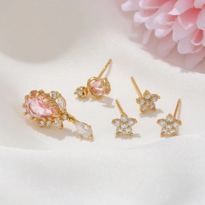 Detail of pink pear-shaped stone earrings and gold star-moon zircon stud set on silk