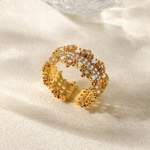 Detailed top view of gold floral pave ring with stars and crystal stones on beige fabric