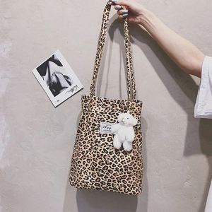 Detailed shot of leopard print canvas tote bag with plush bear charm and Aug brand label