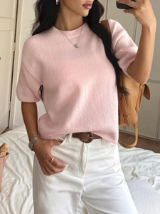 Detail of soft pale pink short sleeve knit sweater styled with white pants and brown belt