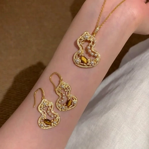 Golden filigree gourd jewelry set with tiger eye stones and pearls worn on model arm
