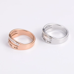 Close-up of minimalist Roman numeral rings in rose gold and silver with inlaid crystals