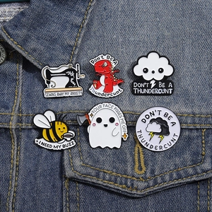 Detail of creative enamel pins on denim jacket featuring humorous quotes and cartoon icons