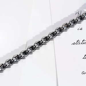 Detailed close-up of retro stainless steel skull and wing links on a silver bracelet
