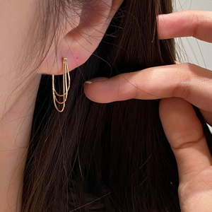 Detailed close-up of golden multi-layer tassel earrings worn by a model in soft lighting