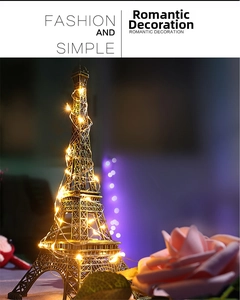 Eiffel Tower metal decorative lamp wrapped with warm yellow LED string lights on floral background