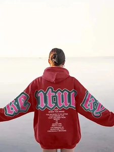 Macro detail of green STURDY lettering print on a burgundy oversized street hoodie