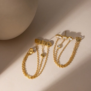 Macro detail of gold tassel earrings featuring clear cubic zirconia and sleek chains