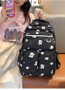 Detail of a black multi-pocket backpack with cute print held by a model in a casual setting