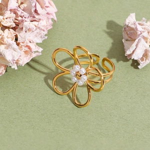 Bague fleur en or 18 carats avec perles et découpes sur fond vert texturé