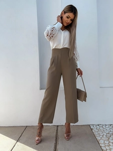 Detailed view of white lace hollowed-out shirt sleeves and olive green trousers
