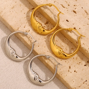 Minimalistische 18K Gold und Silber Mondgesicht Ohrringe auf rustikalem Stein Hintergrund