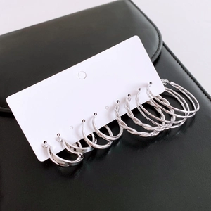 Dettaglio di orecchini a cerchio in argento con design intrecciato su cartoncino bianco