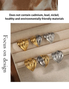Macro view of textured heart stud earrings in gold and silver finish on beige velvet