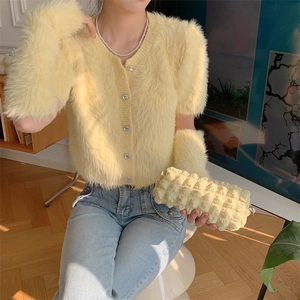 Close-up of pale yellow faux fur knit cardigan with sparkling rhinestone buttons