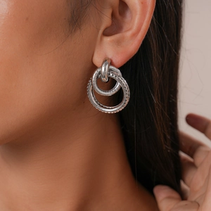 Close-up of geometric interlocking silver earrings with mesh texture on professional model