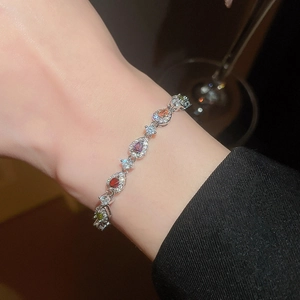 Detailed macro view of vibrant teardrop zircons on a silver bracelet worn on a wrist