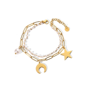 Détail du bracelet en acier doré à plusieurs rangs avec breloques lune, étoile et perles