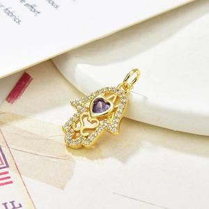 Macro shot of golden Hamsa pendant with purple heart crystal and cubic zirconia accents