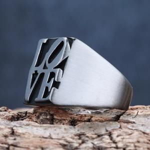 Unisex LOVE letter ring in brushed stainless steel on a rustic wooden base
