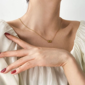 Minimalist gold plated titanium necklace with rectangular pendant worn on a female neck