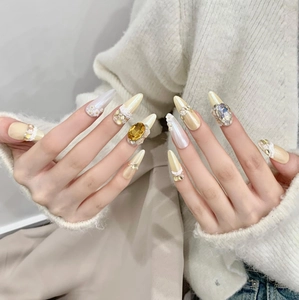 Detailed close-up view of luxury handcrafted press-on nails with gold gems and pearl accents