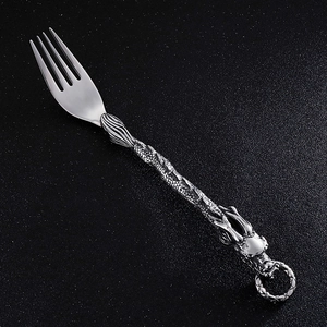 Detailed close-up of a vintage stainless steel fork with an ornate dragon handle carving