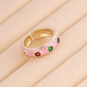 Macro shot of gold adjustable ring with pink enamel and colorful zircon gemstone inlays