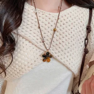 Boho amber tiger eye flower pendant necklace with resin heart on beige knit sweater