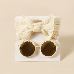 Detail von Baby-Stirnband mit Strickschleife und Gänseblümchen-Brille auf Displaykarte