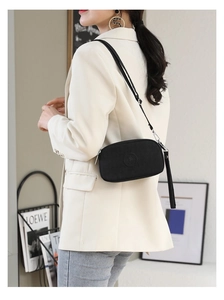 Detailed view of the black nylon crossbody bag size and fit on a model shoulder