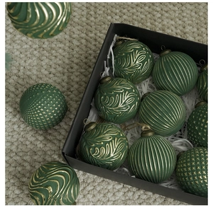 Detailed macro view of 8cm dark green Christmas balls with gold embossed patterns in a gift box