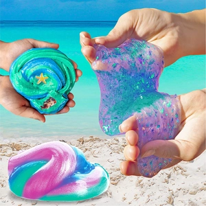 Detail of colorful gradient slime kit with glitter and sea-themed charms on a beach