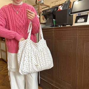 Detailansicht einer weißen Polka-Dot-Canvas-Tasche mit Falten und Markenetikett