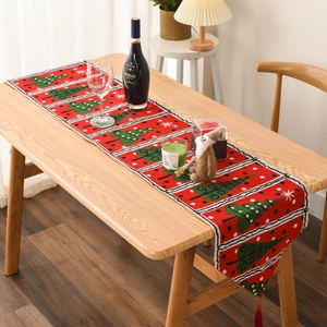 Close-up of red Christmas table runner with knitted tree patterns and festive tassels