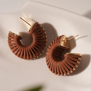 Detail view of brown faux leather threaded hoop earrings with golden metal base accents